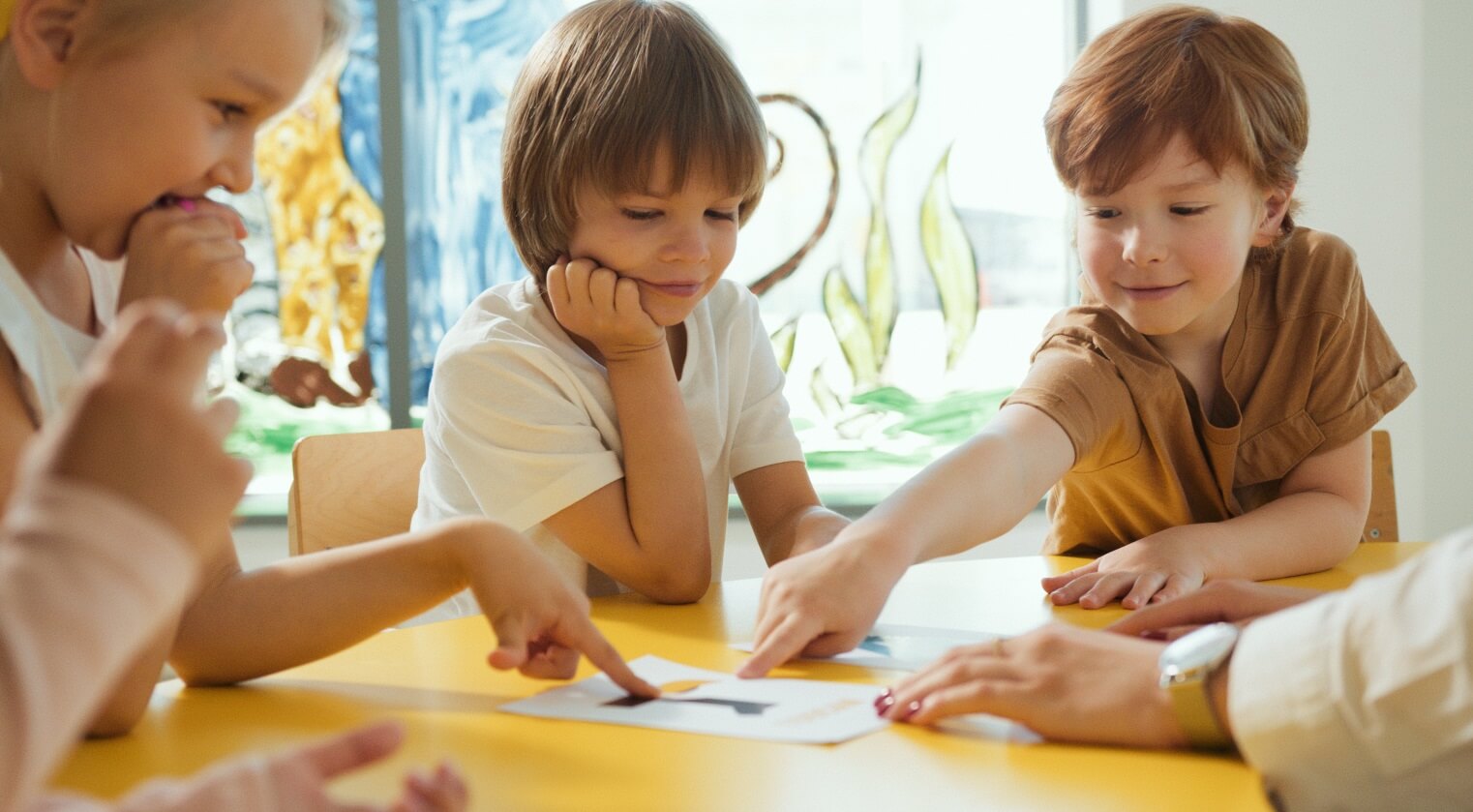 3 children smiling and pointing at a picture