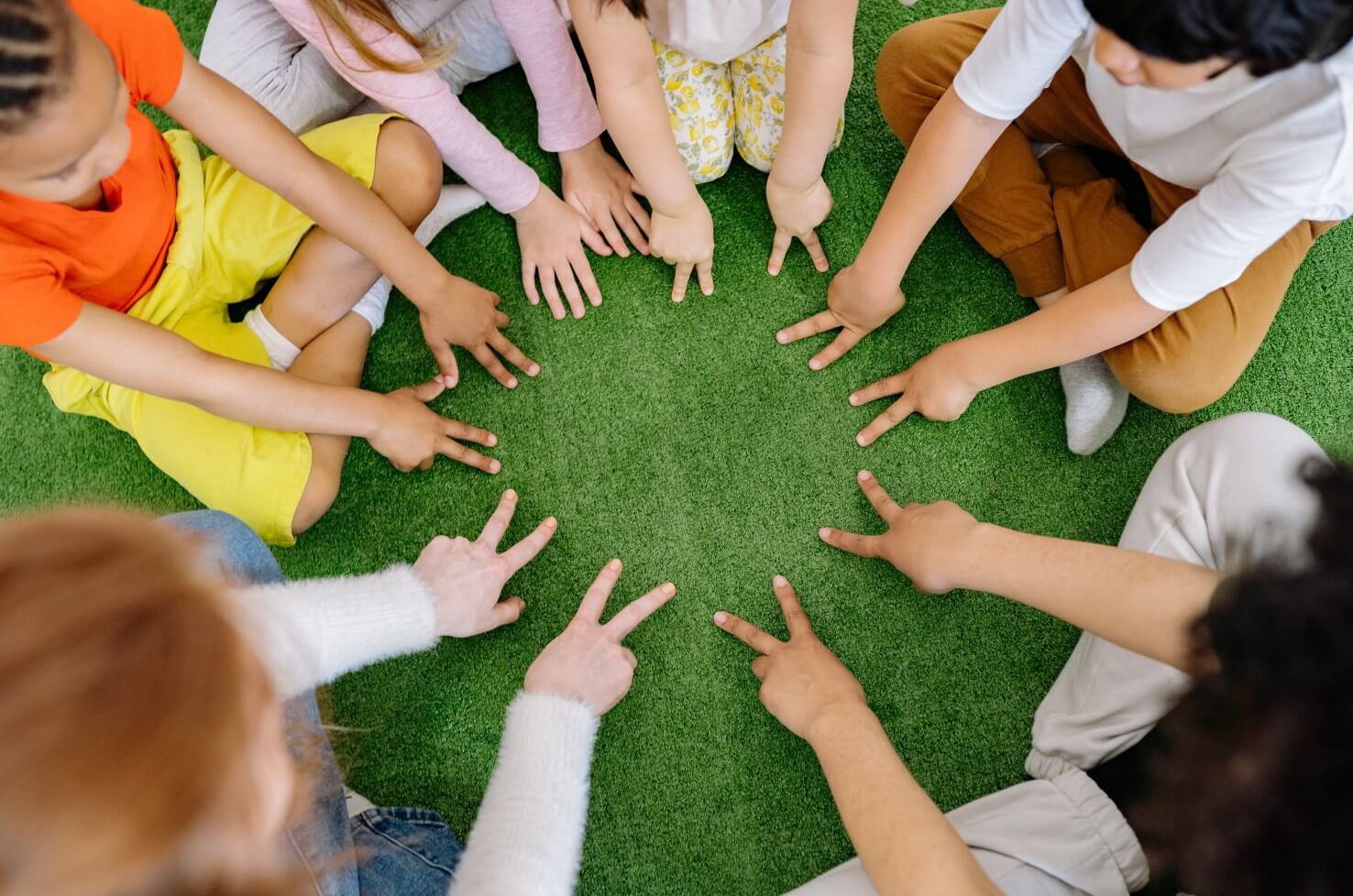 Children sitting in a circle with their hands on the ground