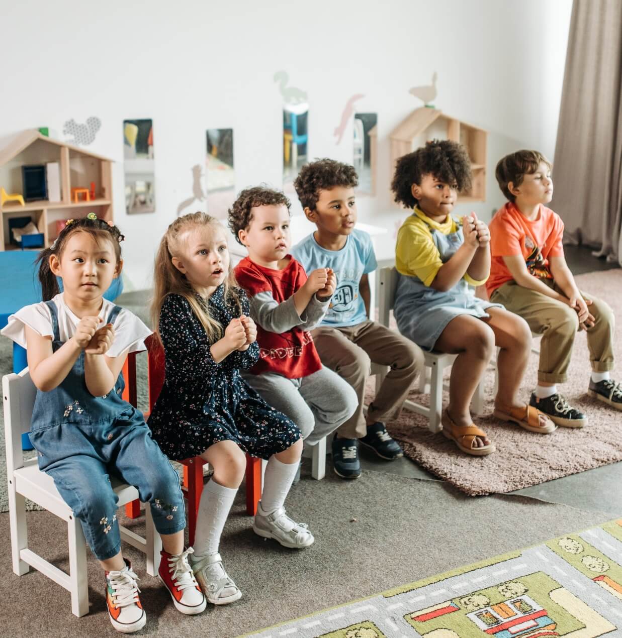 6 children sitting on chairs in a row and playing a drama game