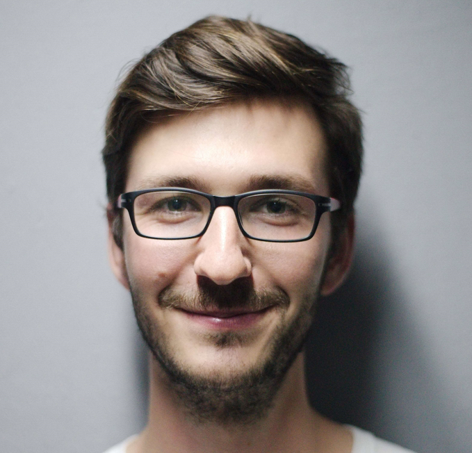 A smiling man with brown hair and glasses